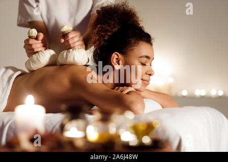 Herbal massage. African-american girl having back massage Stock Photo