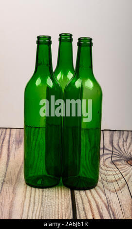 Three empty green glass wine bottles on a wooden table Stock Photo