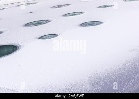 Aerated pond with lines of holes made in ice, that is covering fish pond during winter season, aiming to protect fish population. Seasonal background Stock Photo