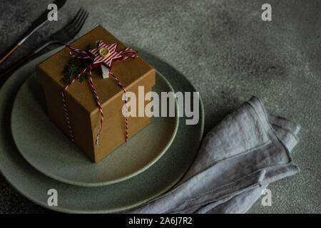 Christmas table setting with gift box on concrete background Stock Photo