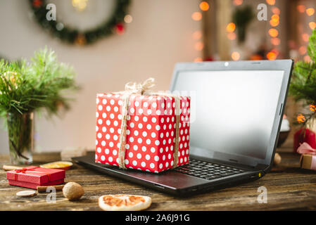 Gift red box with white polka dots on the laptop. Purchase discounts for Christmas in online stores on new year's eve Stock Photo