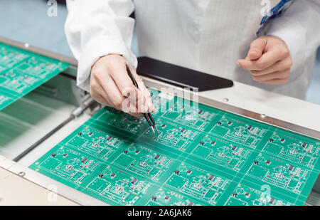 Technician assembling electronic product by inserting components into board Stock Photo