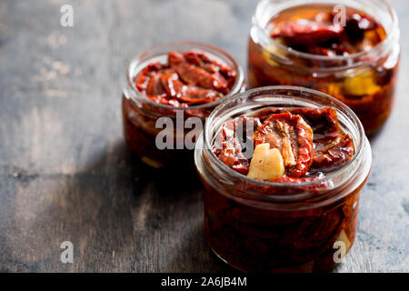 Sun dried tomatoes with olive oil in a jar on wooden background Stock Photo