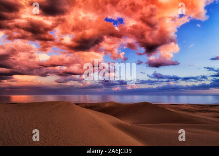Bright bloody pink clouds over Pacific ocean after rain and storm over sand dunes of Stockton beach in Australia - colourful scenic seascape view. Stock Photo