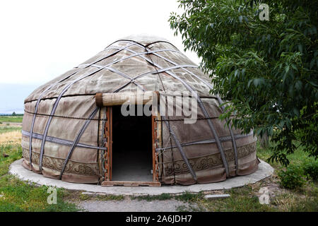 White yurt with an open entrance next to a tree. Kyrgyzstan Stock Photo