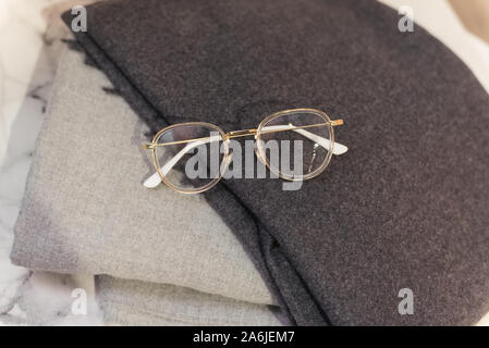 Image glasses on the background of gray scarves. Glasses for the office, stylish autumn scarves. Stock Photo