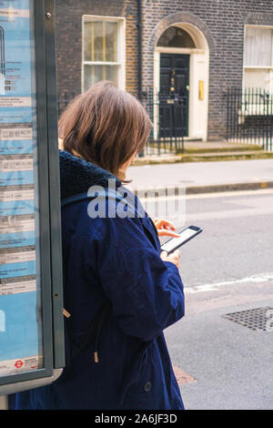 Woman on her mobile phone at a bus stop Stock Photo