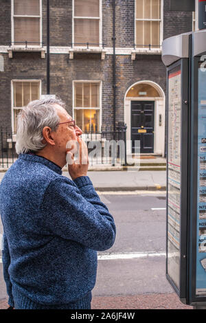 middle-aged man looking at bus time table at bus stop Stock Photo