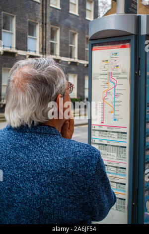 middle-aged man looking at bus time table at bus stop Stock Photo