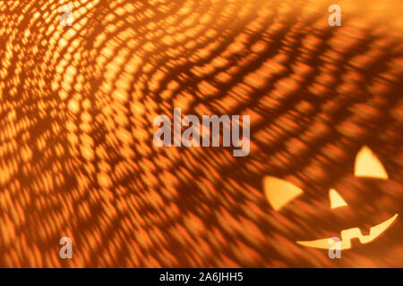 Halloween scary pumpkin face on dark orange paper background. Shadow from the fire. Halloween horror background. Stock Photo