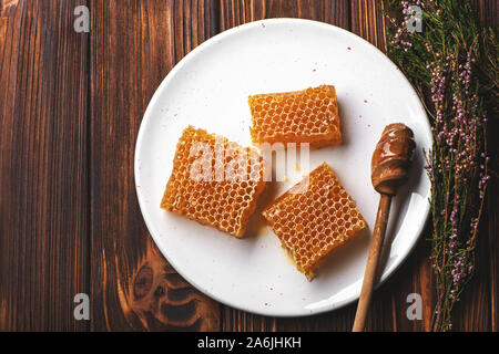 Honeycombs on white plate on wooden background. Stock Photo