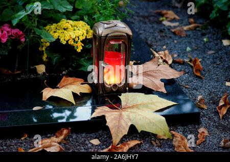 Grave light in evening mood on a cemetery with autumn leaves Stock Photo