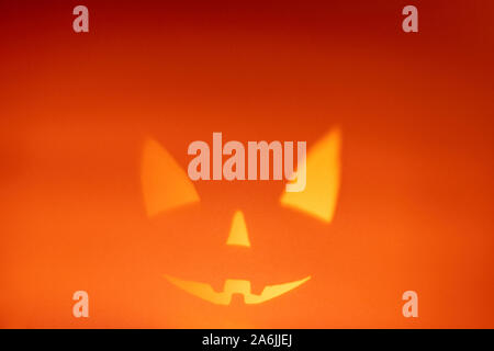 Shadow of halloween scary pumpkin face on dark orange paper background. Shadow from the fire. Halloween horror background. Copy space. Stock Photo