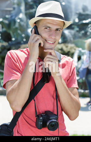 young man with phone and camera outdoors Stock Photo
