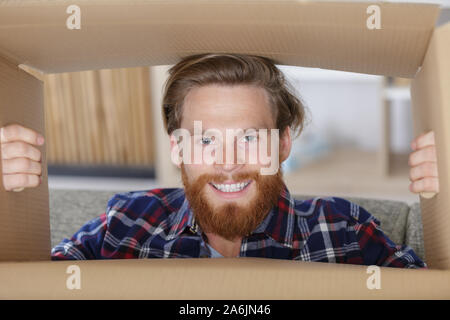 bearded man looking through a cardboard box Stock Photo