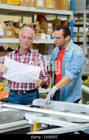 workers looking at blueprint in warehouse Stock Photo