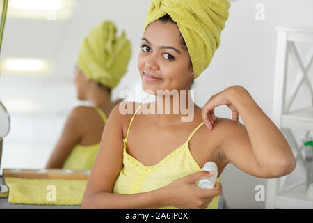 young woman applying roller deodorant in her armpit Stock Photo