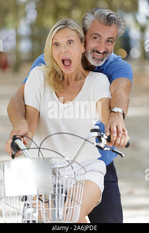 happy mature couple having fun on a bicycle Stock Photo