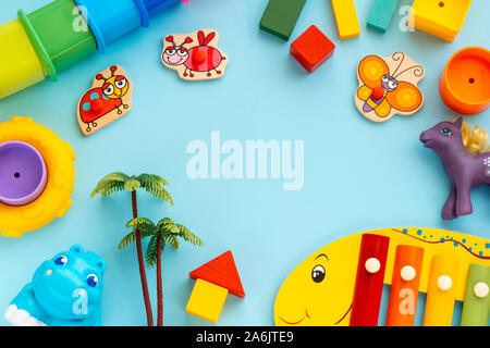 Top view on children educational games, frame kids toys blue paper background. Cubes, circles, ladybag, hippopotamus, horse, palm and xylophone. Flat lay, copy space. Moscow, Russia - August 10, 2019 Stock Photo