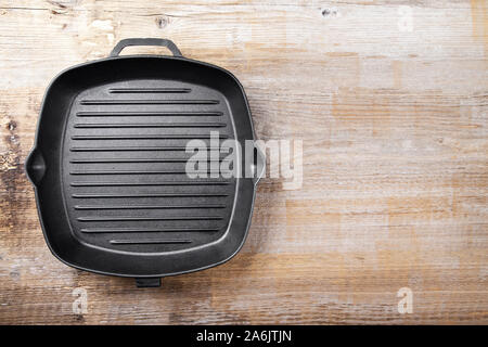 New empty cast-iron grill pan with two handles on a wooden background. place for text Stock Photo