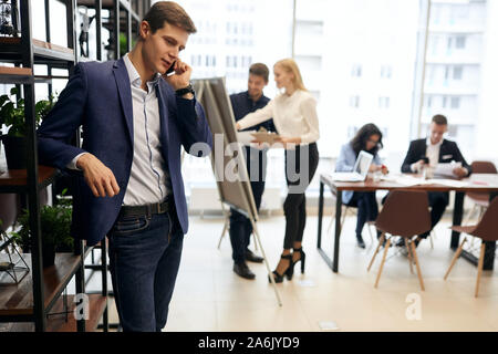 successful businessmen making an appointmnet to clients with mobile phone, his colleagues preparing for a business meeting, conference . Stock Photo