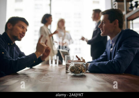 blurred photo of business people having pleasant conversation, three colleagues are talking in the backgroud of the photo. mn teaching new employee, g Stock Photo