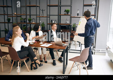 young successful creative businessman sharing ideas of successful business plan, man introducing people with the results of survey Stock Photo