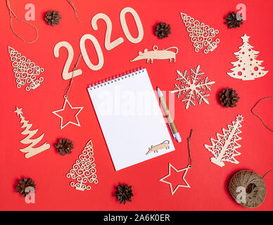 Creative festive christmas mockup on red background with diy handmade wooden xmas decorations, numbers 2020, rat, cones and copy space for text on whi Stock Photo