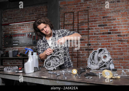 man work with the socket wrench, repair and cleaning engine parts on the workbench in home garage workshop, diy concept Stock Photo
