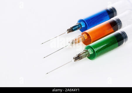 Three syringe filled with colorful liquids against white background Stock Photo