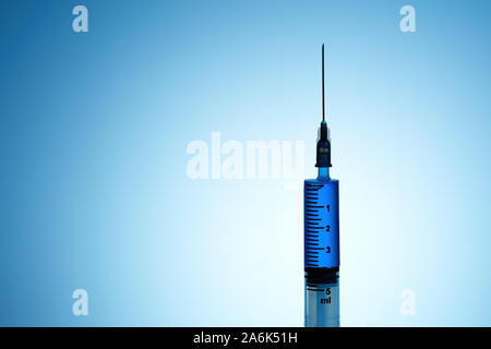 Syringe filled with blue liquid on blue background Stock Photo