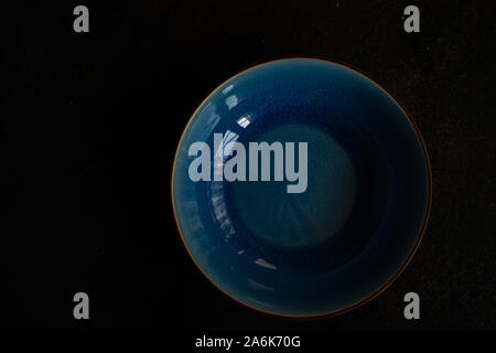 Empty blue ceramic bowl on dark stone background with copy space Stock Photo