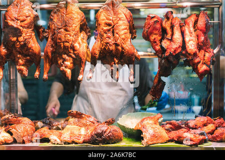 Roasted crispy Chinese duck and pork hanging from window of a street food night market stall - Marinated Asian meat and poultry on display at a local restaurant - cuisine, travel and delicacy concept Stock Photo