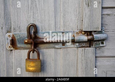 rusty padlock attached to a breton bolt on a grey shed door Stock Photo