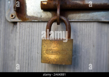 rusty padlock attached to a breton bolt on a grey shed door Stock Photo