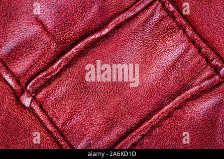 Crumpled red leather texture background. Abstract texture of leather with a seam. Stock Photo