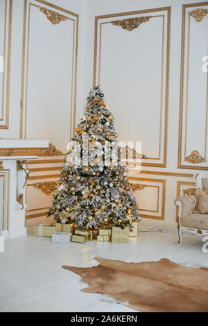 Beautiful decorated golden Christmas tree with present boxes under it in vintage luxurious interior decorated for New year. Concept of Christmas eve Stock Photo