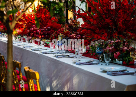 Autumnal table setting in red color decorated with red apples and pomegranate Stock Photo