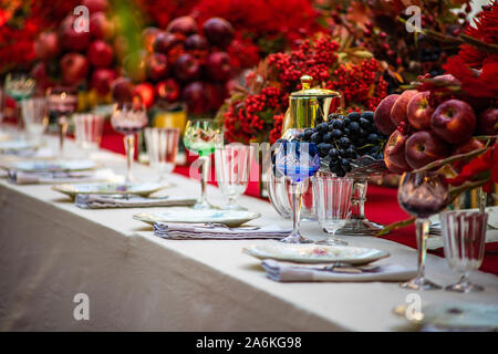 Autumnal table setting in red color decorated with red apples and pomegranate Stock Photo