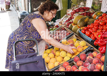Barcelona Spain,Catalonia El Clot,Llegums Cuits,neighborhood fruit produce market grocery store fruit stand,woman,senior,shopping,peaches,peppers,disp Stock Photo