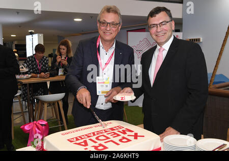 23 October 2019, Bavaria, Munich: Florian Herrmann (CSU, r), Head of the Bavarian State Chancellery and Minister of State for Federal and European Affairs and Media, and Siegfried Schneider (CSU), President of the Bavarian State Centre for New Media (BLM), cut a cake with a logo with the inscription 'XPLR: Media in Bavaria' at the official start of the 33rd Munich Media Days at the Munich Trade Fair Centre. Photo: Felix Hörhager/dpa Stock Photo