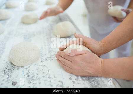 Hands preparing the dough for baking bread in the bakery. Stock Photo
