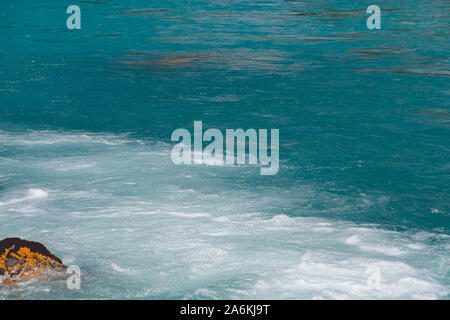 Turquoise water in river with stone shore. Sea tide, seething blue water in mountain stream Stock Photo