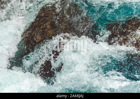 Rough river flow. The blue water of mountain river, the tide on sea with turquoise water and stone banks Stock Photo