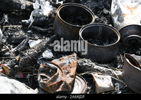 Iron cans burned in fire. Bad ecology, pollution of environment. Nature protection. Stock Photo