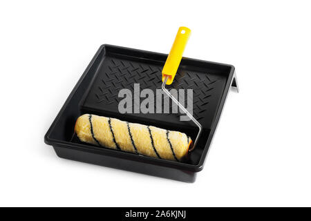 Paint roller with a yellow handle in a black cuvette. Isolated over white background. Stock Photo