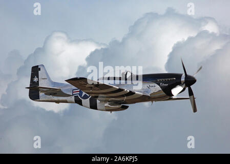 A World War II-era P-51 Mustang fighter aircraft flies through billowing storm clouds. Stock Photo