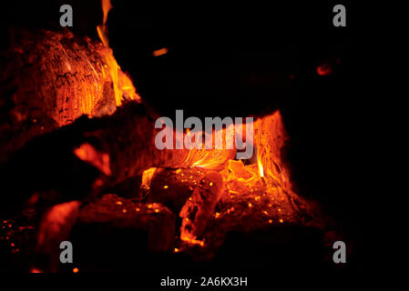 Close up of bonfire with sparks at night. Heat from burning logs and coals in the dark Stock Photo