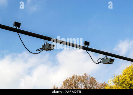 Two pairs of outdoor surveillance camera with sensor installed on a pole above a roadway. Modern automatic traffic control. Against a blue sky. Stock Photo