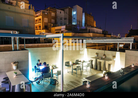 Valencia Spain Hispanic,Ciutat Vella,old city,historic district,Vincci Mercat,hotel,rooftop restaurant,skyline,night evening,man,woman,using laptop,gu Stock Photo